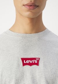 Grå bomulds t-shirt med et rødt broderet Levi's logo. Rund halsudskæring, blød tekstur og korte ærmer.