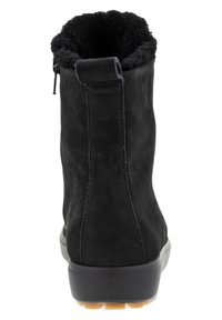 Bottes basses en daim noir avec une doublure en fourrure texturée, une fermeture éclair sur le côté et une semelle en caoutchouc avec un accent beige au talon.