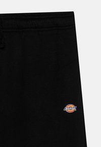 Svarta sweatpants med dragsko i midjan, som har en liten färgglad "Dickies"-logotyp på sidan. Mjukt bomullsblandat material.
