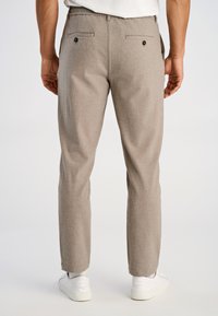 Grijze broek van gestructureerde stof, uitgevoerd in een slim fit ontwerp, met achterzakken met knopen, gedragen met witte sneakers.