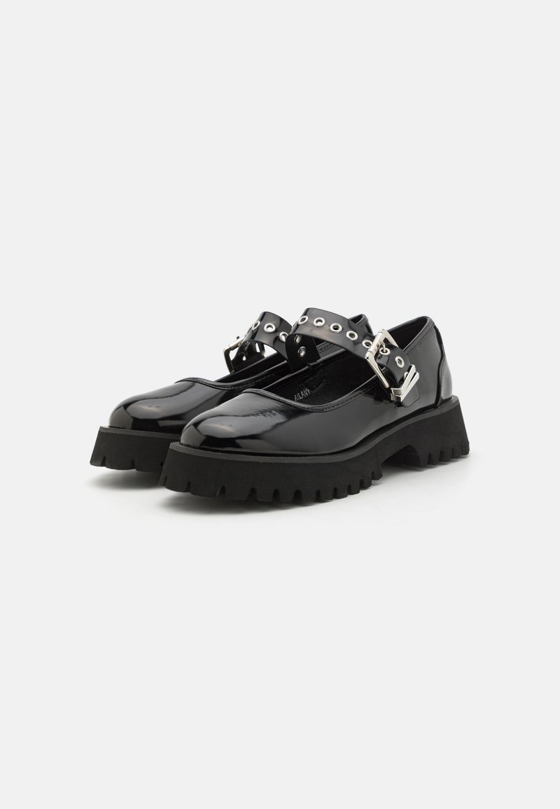 Scarpe in vernice nera con una suola spessa nera, dotate di due ampie cinghie con hardware argentato e ritagli circolari.