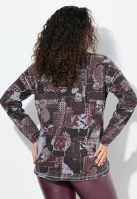 Langsleeve top met een patchworkontwerp in bordeaux, zwart en grijs met diverse texturen; ronde halslijn en een ontspannen pasvorm.