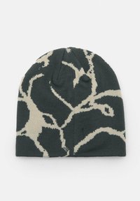 Fekete-fehér kötött sapka absztrakt ágtípusú mintával, puha textúrával és lekerekített tetejével, fehér háttérre fektetve.