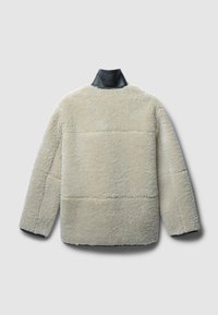 Fleecejacke mit einer cremefarbenen Textur, ausgestattet mit einem schwarzen Lederkragen und langen Ärmeln. Der Rücken hat eine kastenförmige Form mit einer Nahtdetail.