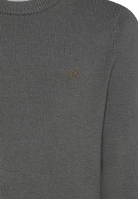 Grauer Strickpullover mit rundem Ausschnitt. Mit kleinem braunem Logo auf der Brust und einem strukturierten Strickmuster.