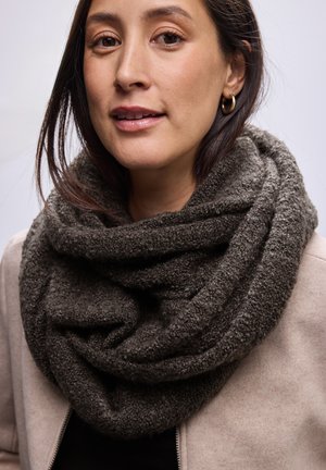 Écharpe infini texturée gris foncé en matériau doux, superposée et drapée autour du cou. Portée avec une veste beige claire.