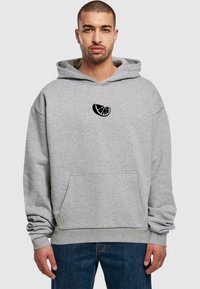 Grauer Kapuzenpullover mit Kängurutasche, ausgestattet mit einem schwarzen Zitrusscheiben-Graphic auf der Brust. Weicher Stoff mit lockerer Passform und verstellbarem Kapuzenzug.