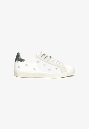 Zapatillas blancas con patrones de estrellas plateadas, detalles en ante gris y un tacón plateado brillante. Presentan cordones blancos y una suela de goma texturizada.