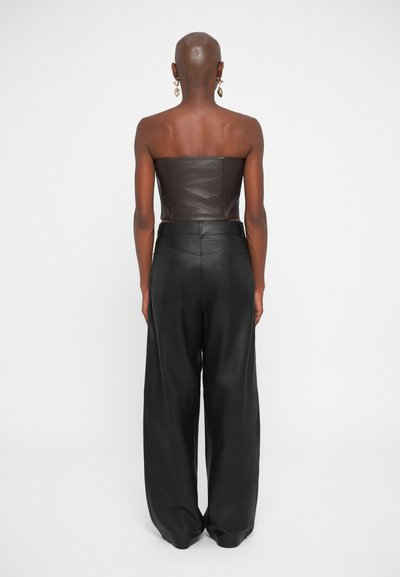 Bruin leren strapless top gecombineerd met loszittende zwarte leren broek, met een gladde textuur en minimalistisch ontwerp.