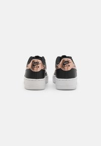 Crne kožne Nike Air tenisice s metalik ružičastim akcentima, bijelim potplatima, podstavljenim ovratnikom i logotipom na peti. Glatka teksturalna završna obrada.