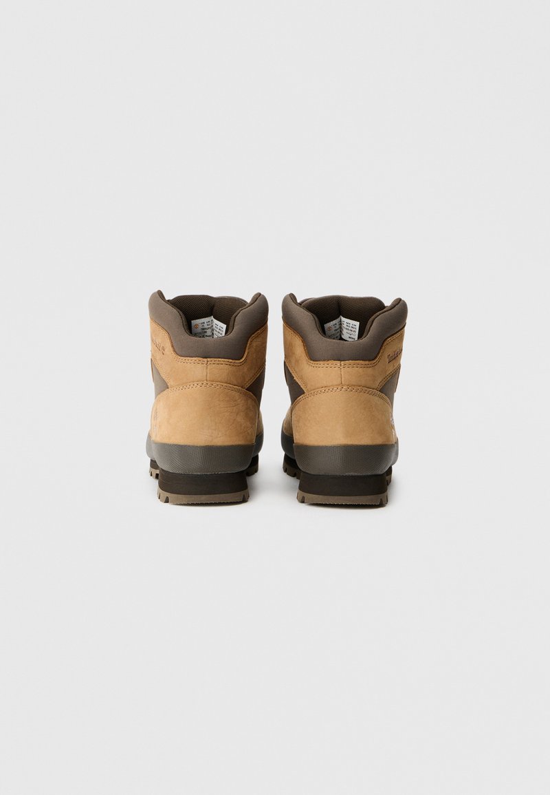 Brown leather hiking boots with padded collars, a gray rubber sole, and textured detailing on the upper. Laces are absent in this view.