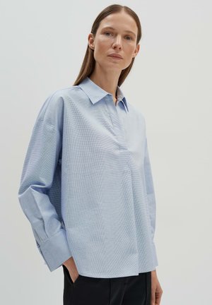 Camicia azzurro chiaro a maniche lunghe con collo a punta, caratterizzata da un tessuto texture, polsini con bottoni e una vestibilità rilassata. Design semplice e linee pulite.