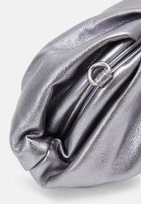 Metallic sølv clutch taske med en blød, krøllet tekstur og rund form. Har en sølv ring detalje på lynlåsen.