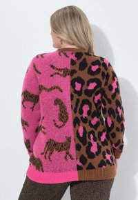 Maglione lavorato a maglia con un design diviso: rosa con stampe animali marroni su un lato, marrone con macchie di leopardo nere sull'altro, orlo a coste.