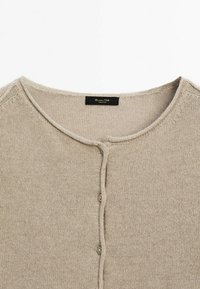 Gilet en tricot beige avec un col rond, présentant une fermeture à boutons, une texture subtile et un design simple. L'étiquette indique "Massimo Dutti."