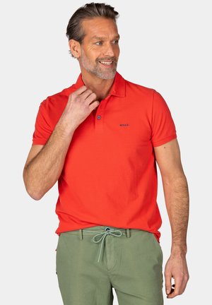 Rode katoenen polo met een kraag en een knoopsluiting van drie knopen, gecombineerd met lichtgroene broek met een trekkoord in de taille.
