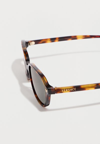Γυαλιά ηλίου με ταρταρούγα πλαίσιο και σκουρούς φακούς, με χρυσό έμβλημα Μέδουσας και λογότυπο «Versace» στο πλάι του βραχίονα.