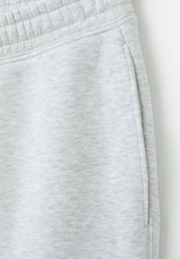 Sive trenirka hlače napravljene od mekog tkanja, s teksturiranom površinom, elastičnim pojasom i bočnim džepovima s diskretnim šavovima.