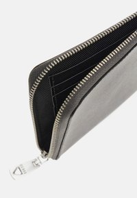 Cartera de cuero negro con un acabado texturizado, que presenta una cremallera plateada y múltiples ranuras para tarjetas en su interior.