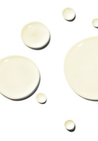 Mehrere durchsichtige beige Flüssigkeitstropfen unterschiedlicher Größe auf weißem Hintergrund.