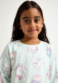 Langärmliges Hemd aus leichtem grünen Baumwollstoff mit einem Einhorn-Print in Pastellfarben und verspielten Wolkenmotiven. Glatte Textur und runde Ausschnittform.