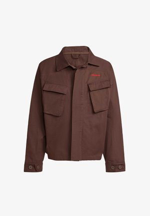 Giacca marrone con due tasche frontali sul petto, chiusura con bottoni e logo rosso sul lato sinistro. Realizzata in tessuto testurizzato.