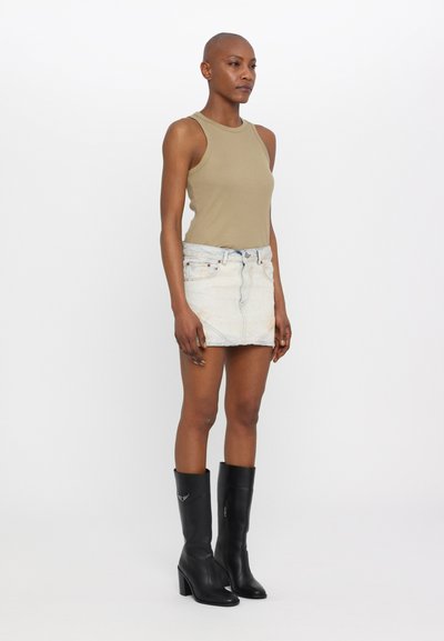 Top fără mâneci de culoare piersică, fustă mini din denim deschis și cizme negre din piele cu toc înalt, până la genunchi, cu detalii argintii.