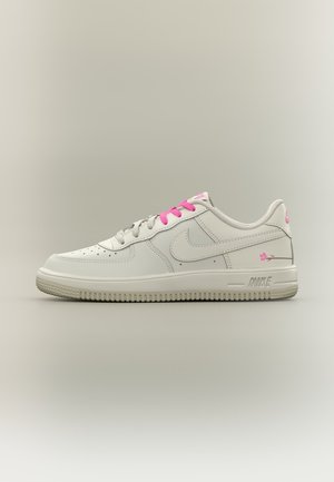 Biały niski sneaker Nike z różowymi sznurówkami oraz kwiatowymi detalami na pięcie i boku, przedstawiony na neutralnym tle.
