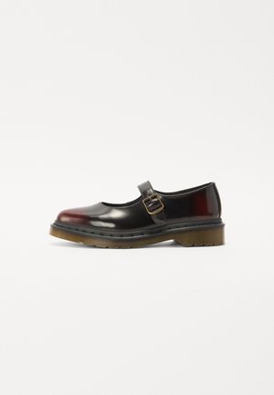 Black patent leather Mary Jane shoe featuring a round toe, a single buckle strap, and a textured rubber sole with a low heel.