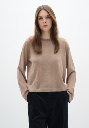 Pull long à manches longues de couleur brun clair avec une texture douce, un col rond et une coupe décontractée, associé à un pantalon noir foncé plissé.
