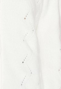 Tessuto bianco a maglia con un motivo ondulato e piccoli fori in tutta la superficie. Morbida consistenza con sottili macchie di colore, che indicano dettagli di design intricati.