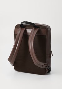 Brown backpack with mesh paneling, smooth leather accents, wide padded straps, and a zippered top. Rectangle shape, structured design.