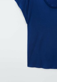 T-shirt en coton bleu à manches courtes avec un col rond sur fond blanc, montrant la moitié supérieure gauche du vêtement.