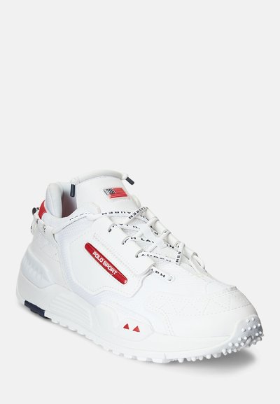 Pantoful sportiv alb are un suprafață sintetică texturată. Prezintă un logo roșu, o talpă gri și o talpă albă cu pete. Detaliile de accent includ un drapel al SUA.