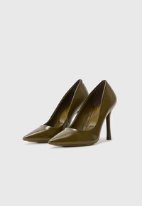 Escarpins en cuir verni vert olive avec un design à bout pointu et un talon aiguille, présentant une finition lisse et brillante.