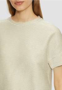Pasiasty sweter w kolorze kremowym i jasnobeżowym, z krótkimi rękawami i ściągaczem wokół szyi, prezentujący delikatnie fakturowany materiał.