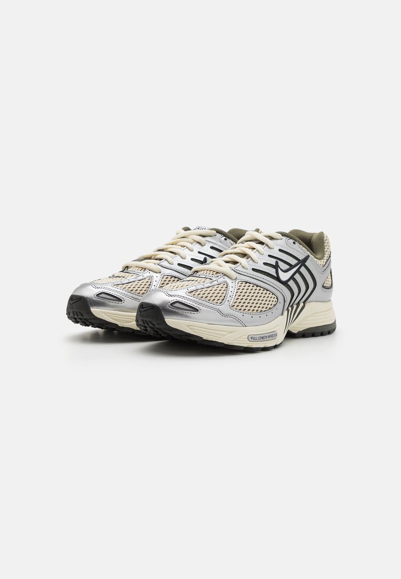 Sneaker mit einem Mesh-Obermaterial in Beige, silbernen Überzügen, schwarzen Akzenten und einer strukturierten Sohle. Verfügt über Schnürsenkel und einen gepolsterten Kragen.