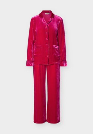 Φωτεινό ροζ βελούδινο πουκάμισο πιτζάμα με μακριά μανίκια και κουμπιά, με δύο τσέπες μπροστά και αντίστοιχο παντελόνι πιτζάμα σε φαρδιά γραμμή.