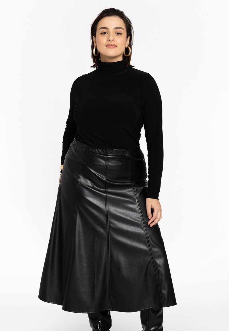 Un haut col roulé noir associé à une longue jupe en cuir noir avec une texture lisse et des détails de couture. La tenue a une taille ajustée.