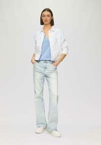 Witte spijkerjack, lichtblauw V-hals shirt, vervaagde wijde jeans, witte sneakers. Glad textuur, casual pasvorm. Geen zichtbare patronen.