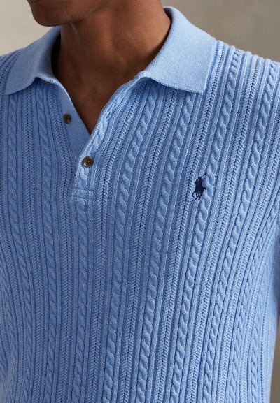 Jasnoniebieska dzianinowa koszulka polo z warkoczowym wzorem, z kołnierzykiem, dwoma guzikami i małym haftowanym logo na piersi.