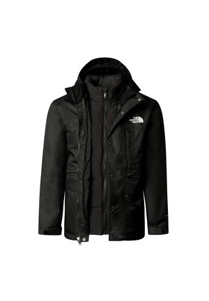 Personne portant une veste North Face noire, un pantalon noir, des chaussures noires, des chaussettes noires, un sweat à capuche gris et un sac à dos jaune et noir.