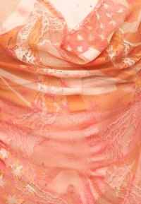 Διάφανη πορτοκαλί και ροζ δαντέλα με λουλουδένια και αστέρια σχέδια, που καλύπτει το πάνω μέρος του στήθους και τον λαιμό ενός ατόμου.