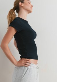 Svart ribbad bomulls t-shirt med korta ärmar, figurnära form och rund halsringning, tillsammans med ljusgrå sweatpants med snörning.