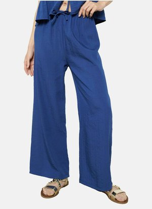 Pantaloni larghi blu in tessuto texturizzato con cintura elastica, abbinati a sandali piatti con dettagli dorati. Fit casual e comodo.