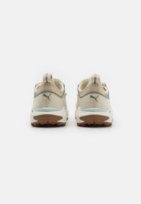 Scarpe da ginnastica beige con tomaia in mesh testurizzato, accenti verde menta e suola in gomma marrone. Caratterizzate da collo imbottito e dettagli riflettenti.