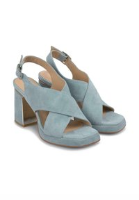 Sandalias de tacón azul de ante con un diseño de tira cruzada, punta abierta y una correa en el tobillo con un tacón cuadrado. Textura suave y hardware mínimo.