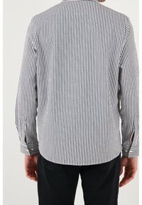 Gestreepte langslavende shirt in marineblauw en wit, met een knoopsluiting, een afgeronde zoom en een enkele achterste vent voor extra comfort.