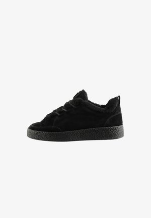 Sort lav sneakersko med tekstureret sål og blødt plysfor, med snørelukning og en trækflig bag på hælen.