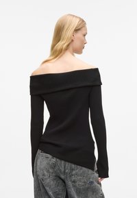 Melnā off-the-shoulder ribota džemperis ar garām piedurknēm, teksturēts audums, pieguļošs dizains un nedaudz garāks aizmugurējais malš.